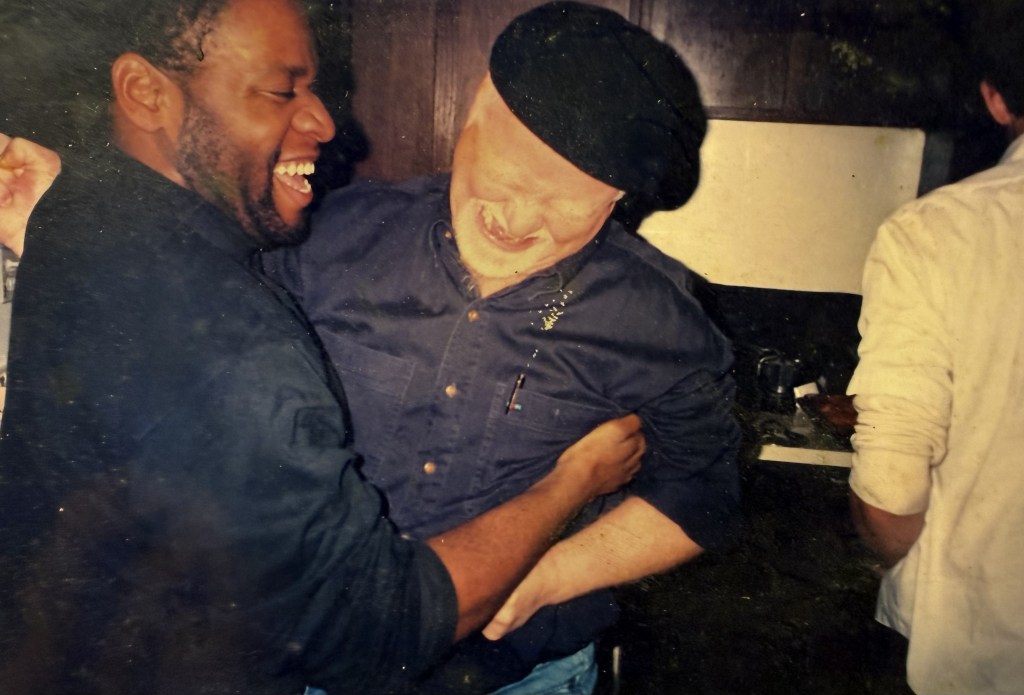 Two men laughing, one embracing the other.