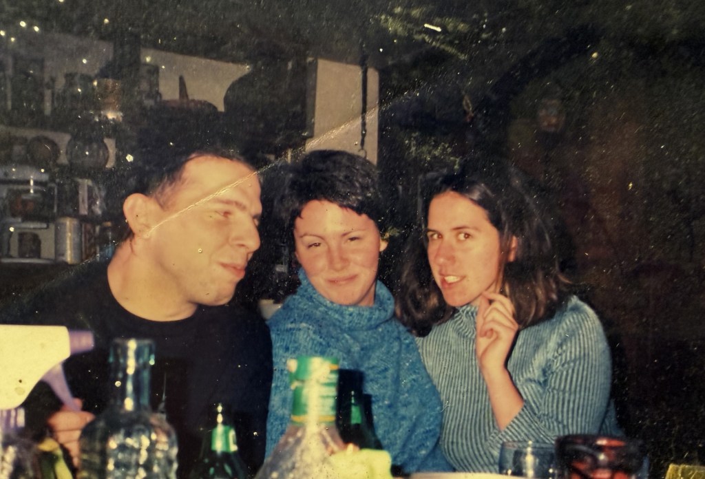 Three people leaning together at a crowded table.
