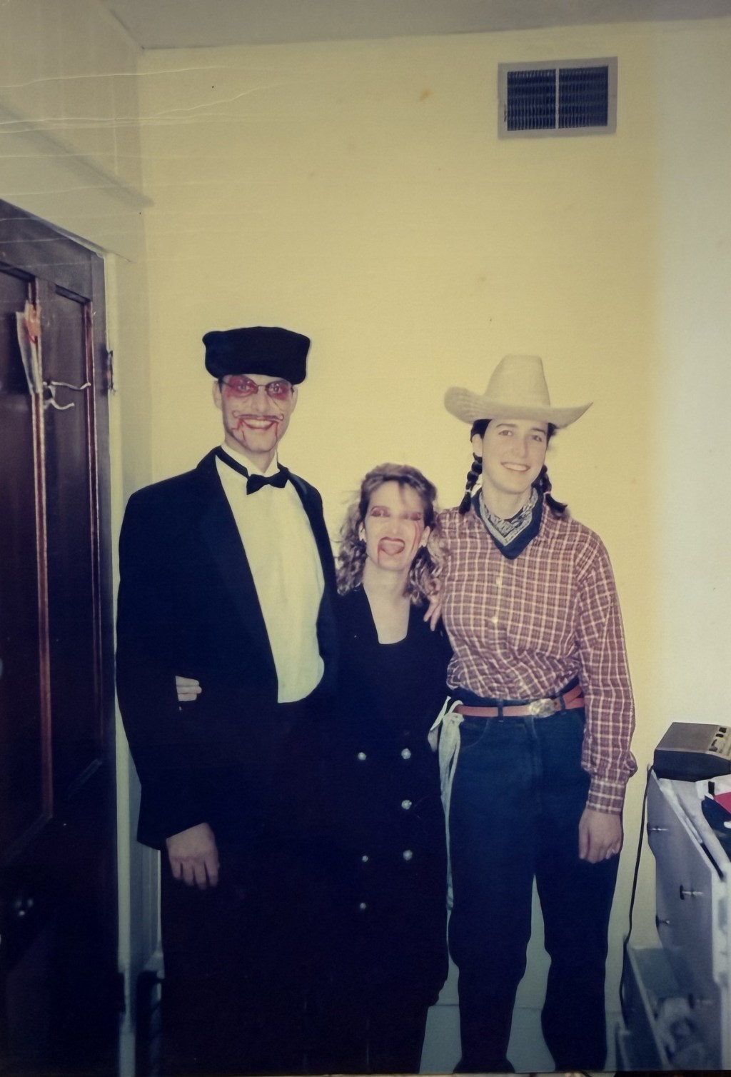 Three people in a tuxedo and fez, black dress, and cowboy hat.