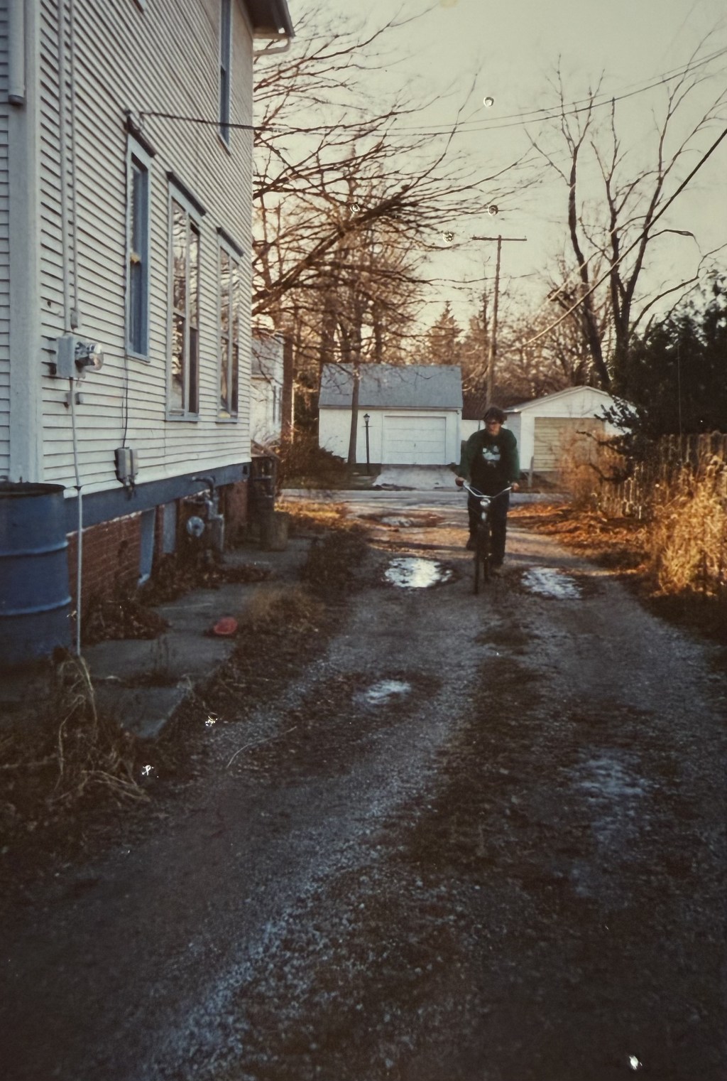 A muddy alley beside the house with a figure at the far end.