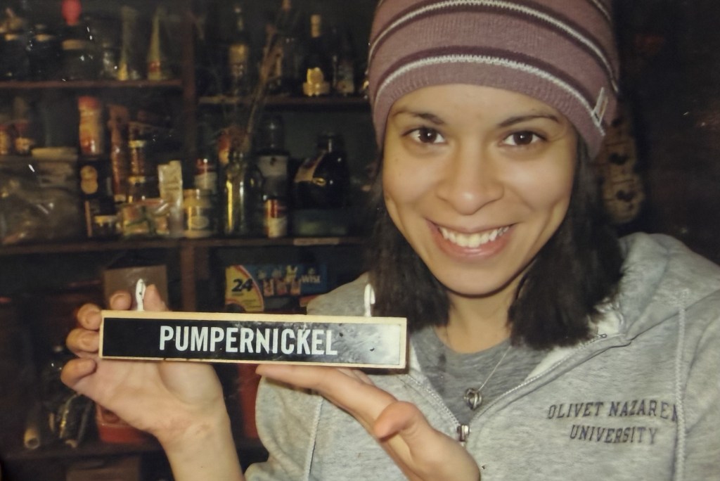 A woman holding a nameplate reading PUMPERNICKEL.
